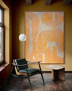 a chair sitting in front of a painting on the wall