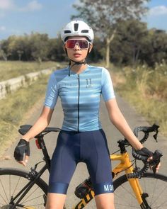 a woman is posing with her bike on the road