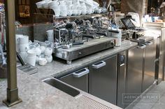 a coffee machine sitting on top of a counter next to a bunch of white cups