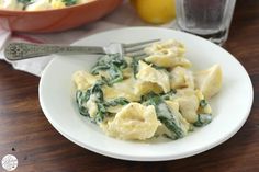 a white plate topped with pasta and spinach