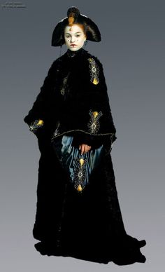 a woman dressed in black and gold is standing with her hands on her hips while wearing a fur coat