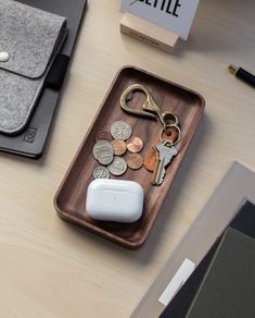 a wooden tray with keys, coins and a computer mouse on it next to a laptop