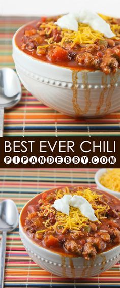 two bowls filled with chili and cheese on top of a striped table cloth next to spoons