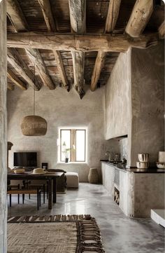 an open living room and dining area with exposed wood beams, stone walls and flooring