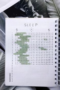 a spiral notebook with a cross stitch pattern on it and the words sleep written in green ink