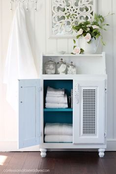 a white cabinet with towels and flowers in it