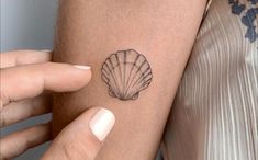 a woman's arm with a small tattoo of a shell on the back of her arm