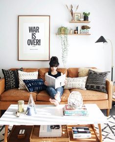 a woman sitting on a couch reading a book