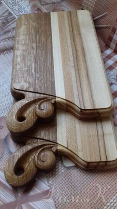 two wooden cutting boards sitting on top of a cloth covered tablecloth with an intricate design