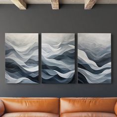 three paintings are hanging on the wall above a couch in a room with leather furniture