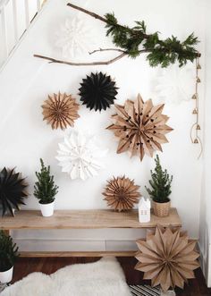 a bunch of paper snowflakes are hanging on the wall above a table with plants