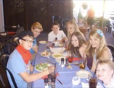 a group of people sitting at a table with plates of food in front of them