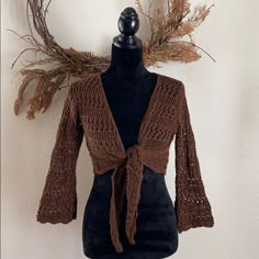 a mannequin wearing a brown knitted cardigan with a tie around the neck