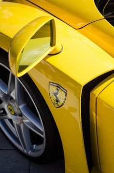 the front end of a yellow sports car with its hood up and emblem on it