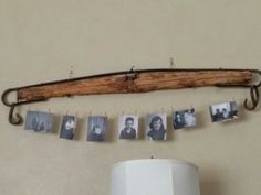 an old wooden stick hanging from a wall with photos hung to it's side