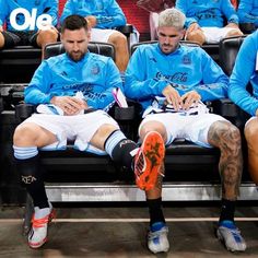 the men are sitting in the dugout with their feet up and writing on paper