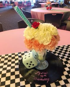 a vase filled with flowers sitting on top of a black and white checkered table