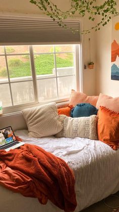 a bed with pillows and blankets on top of it in front of a large window