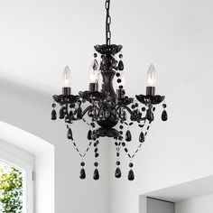 a black chandelier hanging from the ceiling in a room with white walls and windows