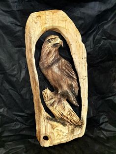 a carved wooden bird sitting on top of a piece of wood with a black background