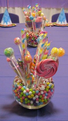 there are many candy candies in the glass vase on the purple tablecloths