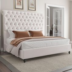 a large white bed sitting on top of a carpeted floor next to a window