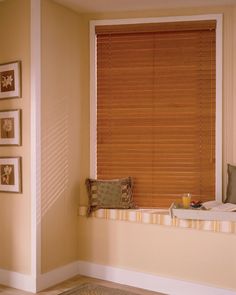 an empty window seat in a room with blinds on the windowsills and pictures on the wall