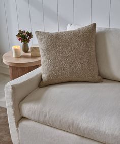 a close up of a couch with a pillow on it and a table in the background