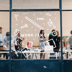 people standing in front of a shop window with the words work / shop written on it