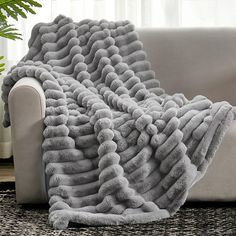 a couch with a blanket on top of it in front of a potted plant