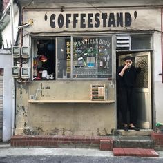 a woman standing in the doorway of a coffee shop with her hand on her face