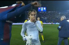 two soccer players are standing on the field and one is covering his mouth with his hand