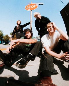 four young men sitting on the ground with one holding his hand up to his head