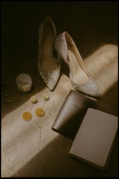 a pair of shoes sitting on top of a floor next to a book and some coins