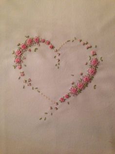 a heart made out of pink roses on a white sheet