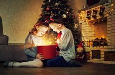 two children are sitting on the floor reading a book with lights coming out of it