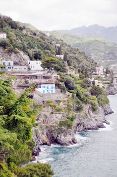 houses on the side of a cliff by the ocean