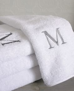 three white towels stacked on top of each other with the letters m and m printed on them