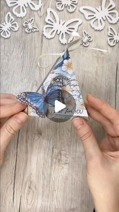 two hands are holding an origami butterfly