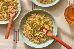 three bowls of noodles with chopsticks on a table next to a glass of beer