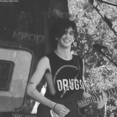 a young man holding a guitar while standing in front of a microphone