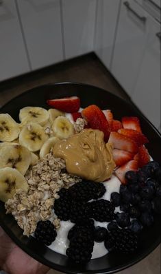 a bowl filled with yogurt, granola, fruit and peanut butter on top of it