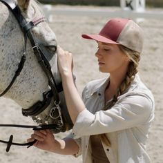 a woman is holding the bridle of a white horse