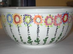 a bowl with flowers painted on it sitting on top of a white tablecloth covered table