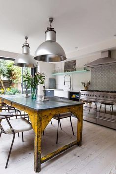 a kitchen with an island table and two lights hanging from it's ceiling over the stove