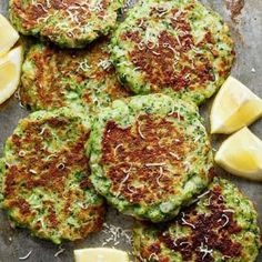 several crab cakes with lemon wedges and parmesan cheese sprinkled on top