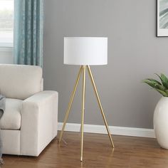 a white lamp sitting on top of a wooden floor next to a couch and chair