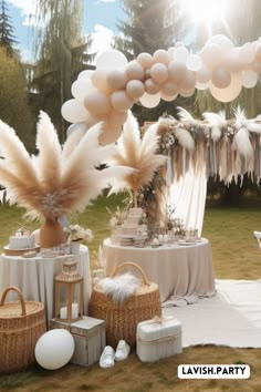 an outdoor party setup with balloons, table cloths and white decorations on the grass