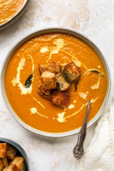 a bowl of soup with croutons on the side and a spoon next to it