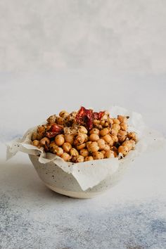 a white bowl filled with chickpeas on top of a marble counter next to a red pepper